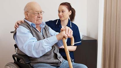 young nurse hugging senior man in wheelchair